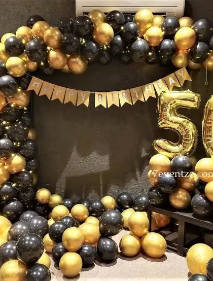 A black and gold balloon arch with large foil numbers for a 50th birthday celebration.