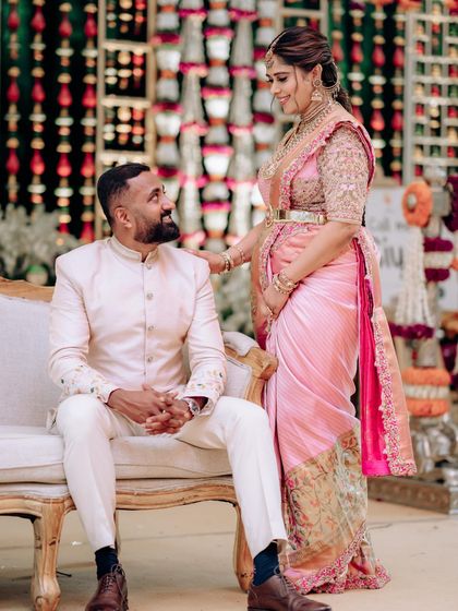 A candid moment from my baby shower. My husband is seated while I stand beside him, showing the beautiful drape of my saree and the intricate work on my blouse.