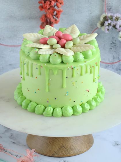 A beautiful light green drip cake for Easter, decorated with delicate white chocolate leaves. A fresh and elegant choice for your celebration.
