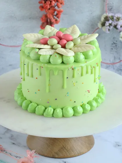 A lovely light green Easter drip cake with delicate white chocolate leaf decorations.