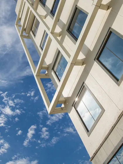 A detail shot of the Venkateshwar Hospital's facade, showing the interplay of geometric forms and the reflection of clouds in the windows. This highlights the clean, modern aesthetic of the building.