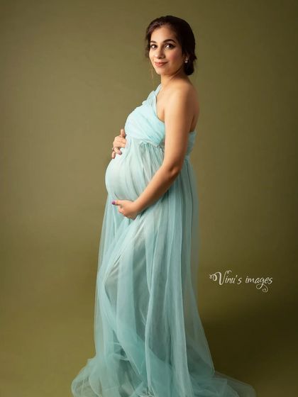 A simple and elegant portrait of the mother-to-be in a light blue gown. The clean background and her gentle pose create a serene and timeless image.