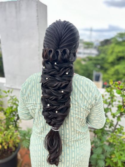 A clear, centered shot of the sculptural braid with pearl details, a masterpiece of hairstyling.