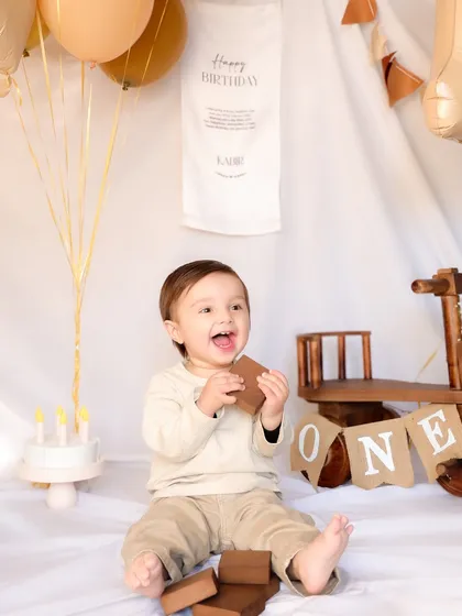 A baby boy enjoys a chocolate treat during his first birthday cake smash session. His happy, messy face is a testament to the fun and spontaneity I encourage in these shoots.