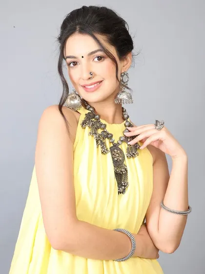 A smiling portrait from the yellow dress shoot, showing how the makeup appears fresh and natural. The look features a classic bindi and nose ring, styled for a traditional yet modern appeal.