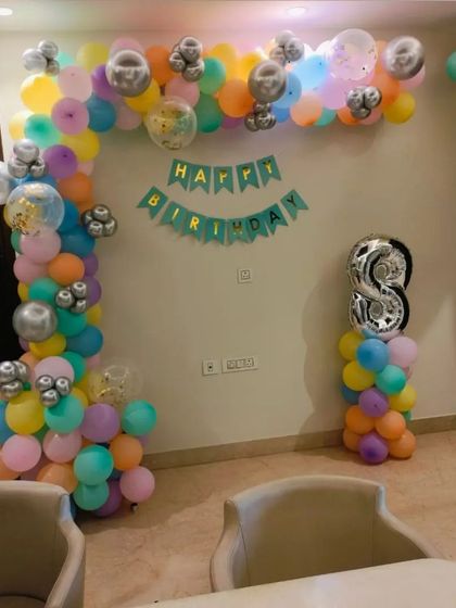 A colorful balloon arch for a home birthday party. This setup uses a pastel palette with silver accents and includes a 'Happy Birthday' banner and a number '8' foil balloon.