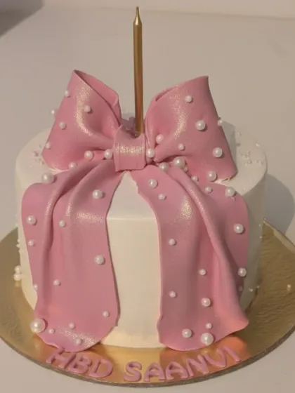 A chic cake for Saanvi's 18th birthday. This butterscotch caramel cake is decorated with a large, shimmering pink fondant bow and delicate pearl details.