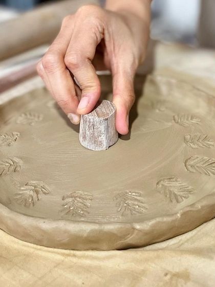 In our one-day workshop, you can learn to make and decorate your own plate. Here, a student is imprinting a pattern onto their hand-built plate.
