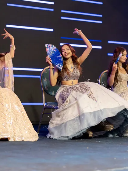 Bridesmaids using fans as props for a seated portion of their choreography, creating a beautiful and unique visual.