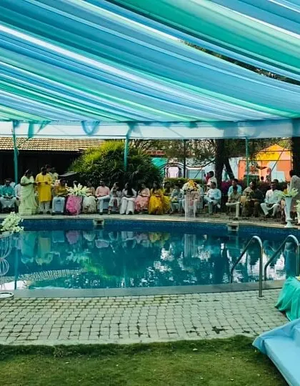 A wide view of the poolside Haldi ceremony we organized. You can see the guests seated and enjoying the beautiful ambiance created by the overhead drapes that reflect in the pool water.