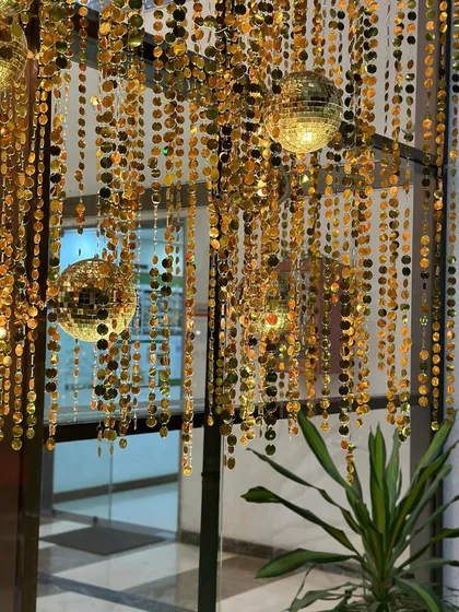 Close-up of hanging decor for a disco-themed event, featuring golden sequin strings and small mirror balls.