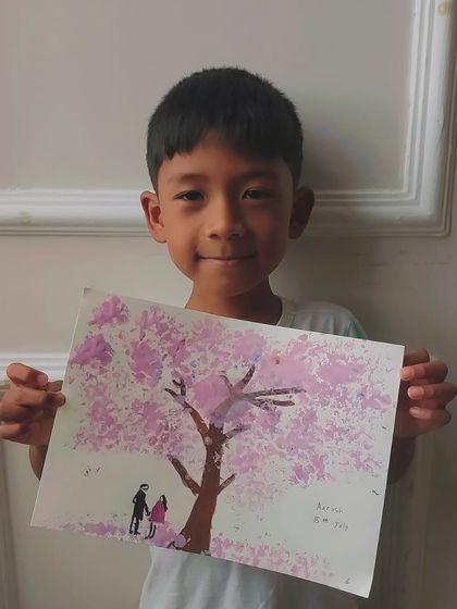 A student from our JRC Palladio class proudly holds his beautiful cherry blossom tree painting.