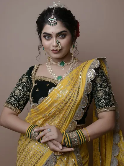 A poised and polished final look by a student. The combination of a dark green blouse with a yellow saree is a classic, and the makeup complements it perfectly.