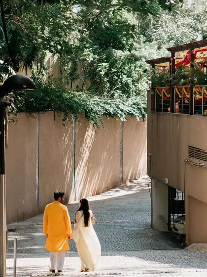 A duplicate of image 69, a couple in traditional yellow and white outfits walks away hand-in-hand.