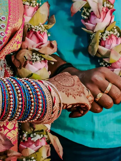 A detail shot focusing on the couple's hands, adorned with wedding rings, bangles, and lotus garlands. This type of photo highlights the beautiful and significant details of a South Indian wedding.