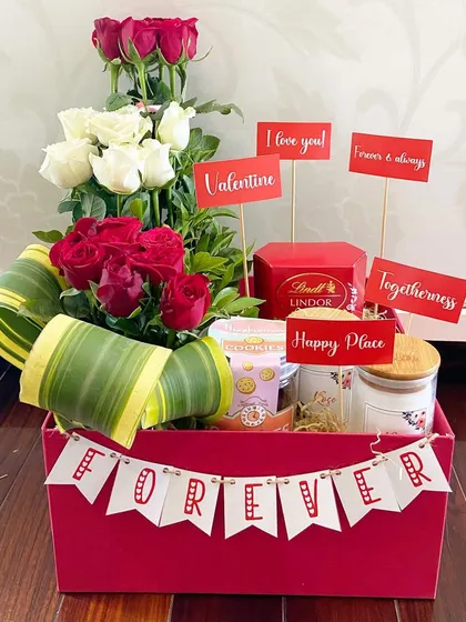 A classic Valentine's Day hamper in a red box, featuring a 'Forever' banner, fresh red and white roses, Lindor chocolates, and cute message cards.