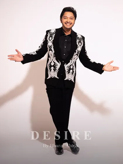 An expressive, full-length view of the black blazer with white baroque embroidery. This piece is designed to offer both commanding presence and freedom of movement.