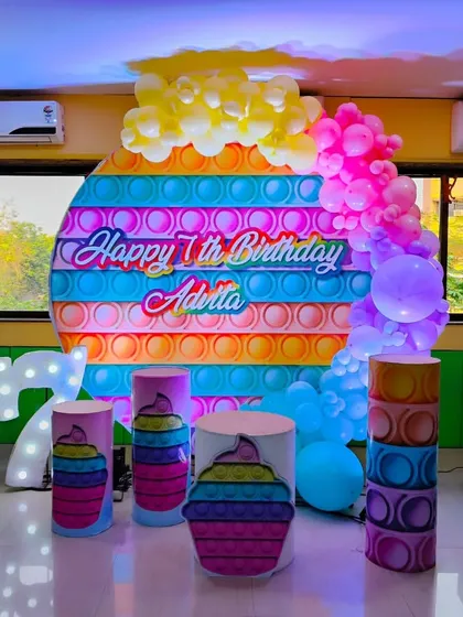We stay on top of the latest trends, like this vibrant 'Pop It' theme for a 7th birthday. The setup includes a custom printed backdrop, themed props, a light-up number '7', and a colorful balloon cascade.