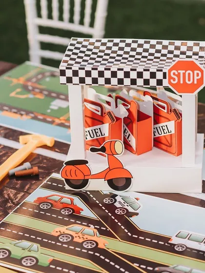 A close-up of the table decor for the 'Road Attack' party, featuring a miniature fuel station and a road-map placemat. The details make the theme come alive.