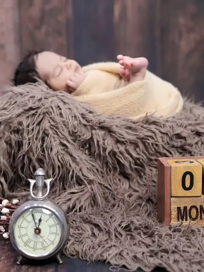A one-month milestone photo featuring a newborn sleeping peacefully next to a vintage clock and calendar blocks. We have many props to mark these special dates.