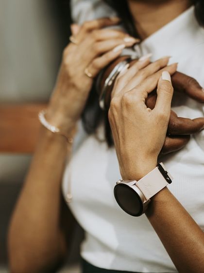 A detailed close-up on the couple's hands and the bride-to-be's watch, capturing the small, intimate details of their connection.