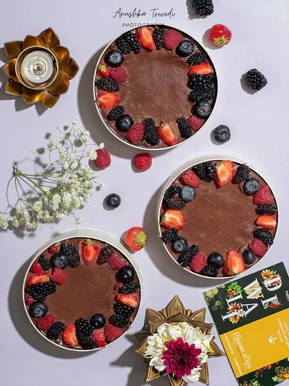 A flatlay of three beautiful berry tarts, styled for Diwali with a lit diya. This shows how a modern dessert can be seamlessly integrated into a traditional festival setting.