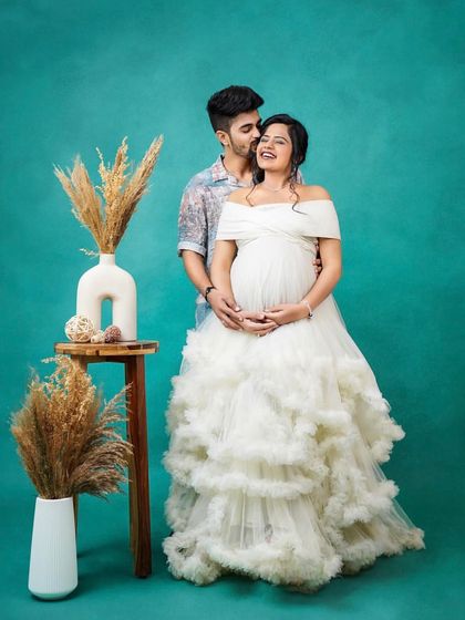 A joyful moment captured in the studio. This couple looks picture-perfect, with her in a stunning white off-the-shoulder ruffled gown and him in a complementary casual shirt.
