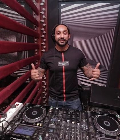 Giving a double thumbs-up from behind the decks. I'm always ready to bring the party and ensure everyone has a great time.