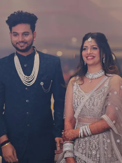 The happy couple posing on their engagement day. Her soft glam makeup and wavy hair perfectly complemented her intricate silver lehenga.