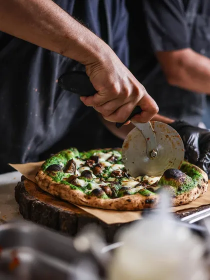 Slicing into our Mushroom pizza with spinach cream sauce. It's a vegetarian favorite that's packed with flavor.