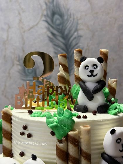 A detail shot of the panda cake, showing the "Happy Birthday" topper and the cute panda sitting amongst the chocolate "bamboo" sticks.