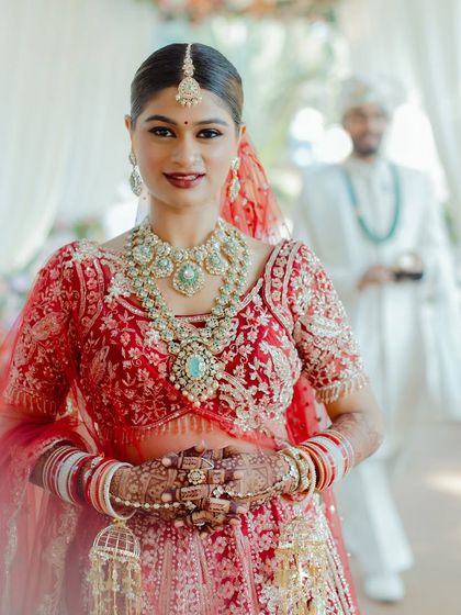 A stunning close-up portrait of the bride, showcasing the radiant skin and perfectly blended eye makeup. The red bindi is a classic touch that completes this traditional Indian bridal look.