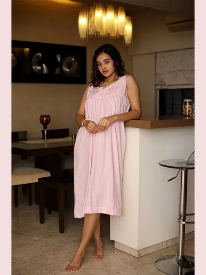 A full-length shot of a pink nightgown in a modern home setting. This helps customers understand the fit and length of the garment while maintaining a relaxed, lifestyle aesthetic for the brand.