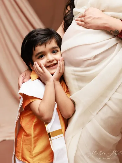A close-up on the excited big brother. His adorable expression as he holds his mother's baby bump is a precious memory of the time before he met his new sibling.