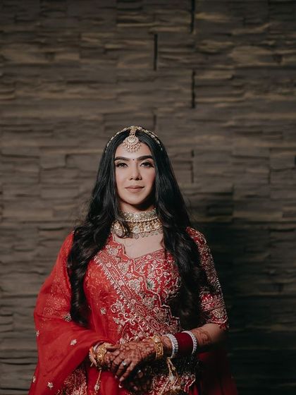 A classic portrait of Nandika against a textured wall. Her direct gaze and confident pose make this a strong and captivating bridal shot.