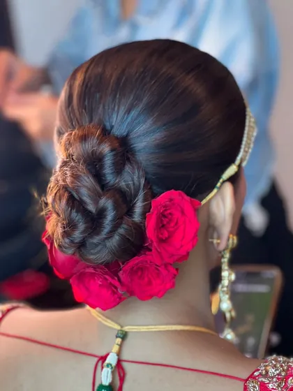 A close-up of the red rose bun, highlighting the rich color of the flowers against the dark hair.
