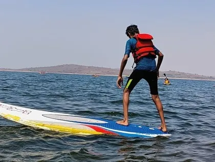 A participant at Vani Vilas Sagar practices his balance on a stand-up paddleboard.