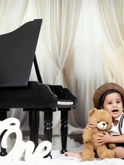 A tender moment as the little boy hugs a teddy bear during his piano-themed shoot.