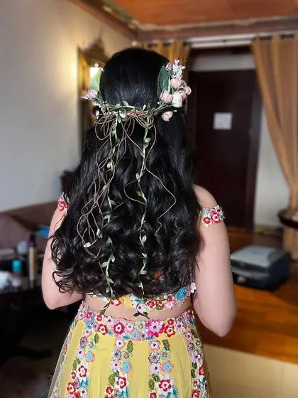 A back view of the bohemian Mehendi hairstyle, showing the intricate floral crown with trailing vines. It's a whimsical and romantic choice for a pre-wedding event.