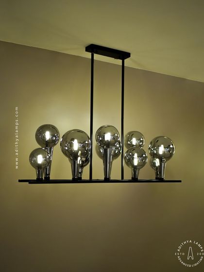 A playful yet chic linear chandelier featuring a series of chrome-finished glass bubbles. The highly reflective surface and modern design make it a striking addition to a kitchen island or a contemporary dining space.