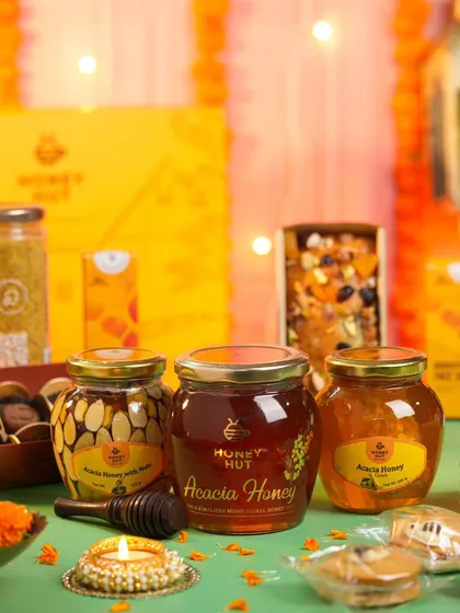 A collection of honey products arranged in a warm, festive setting with diyas and marigolds. This shot is perfect for a brand's Diwali campaign.