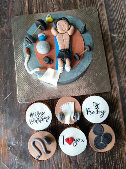 This gym-themed cake and cupcake combo was for a fitness enthusiast's birthday. The cake has a 3D fondant figure doing crunches, surrounded by matching cupcakes with weights and workout gear.