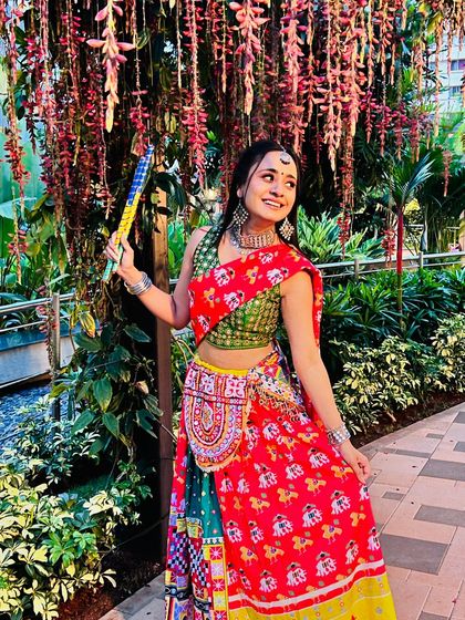 A beautiful shot under a canopy of flowers. The Navratri makeup is fresh and joyful, with a traditional maang tikka completing the look.