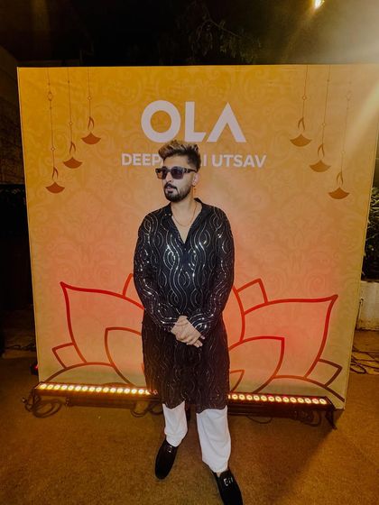 In front of the official OLA Deepavali Utsav backdrop. Ready for a great night of music and celebration.