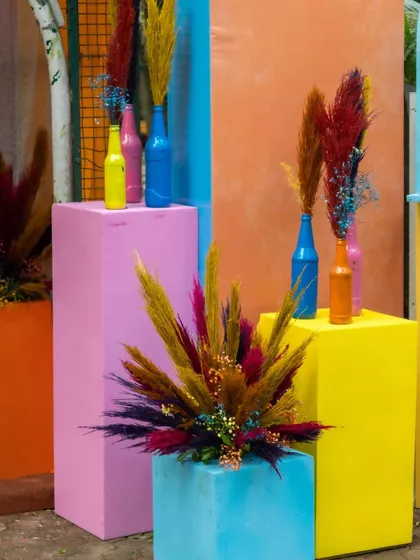 Colorful pedestals and painted bottle vases used at the entrance to reinforce the vibrant, playful theme of the carnival event.