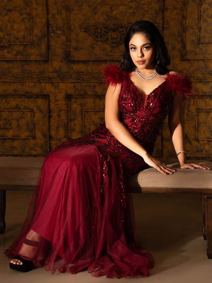 A full-length view of the red feather and sequin gown, showcasing its elegant A-line silhouette and rich, romantic color.