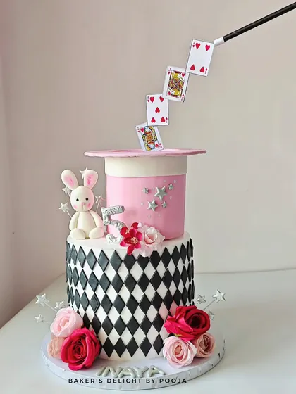 A sprinkle of magic for a special birthday. This two-tier cake features an anti-gravity illusion with playing cards floating out of a magician's hat, complete with a cute fondant bunny and fresh flowers for a spellbinding surprise.