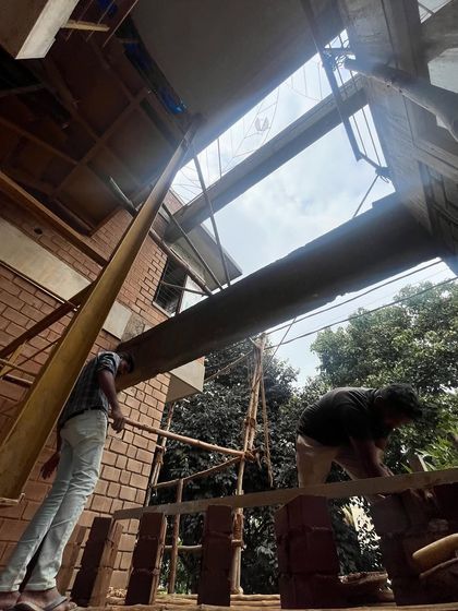 A view from within the construction site, looking up past steel beams to a skylight opening. This shot captures the structural elements before they are concealed, revealing the bones of the building.