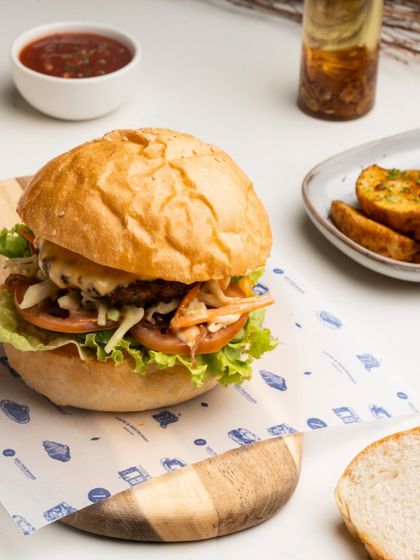 The Ultimate Veg Burger is a hearty meal, with a delicious vegetable patty, fresh lettuce, and tomato, served with potato wedges.