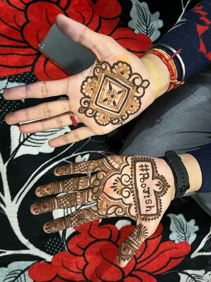 Mehndi for grooms is a growing tradition. Here's a modern take, featuring the couple's wedding hashtag "#RooIsh" on one hand and a complementary geometric design on the other, adding a fun, personal touch to the groom's look.